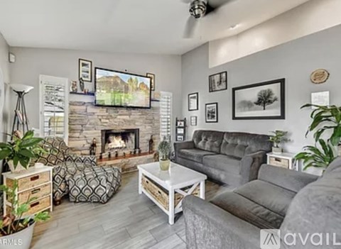 A living room with a grey couch, a white coffee table, and a fireplace with a painting above it.