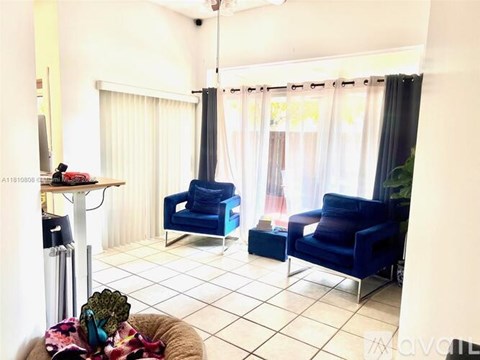 A living room with blue chairs and a white table.