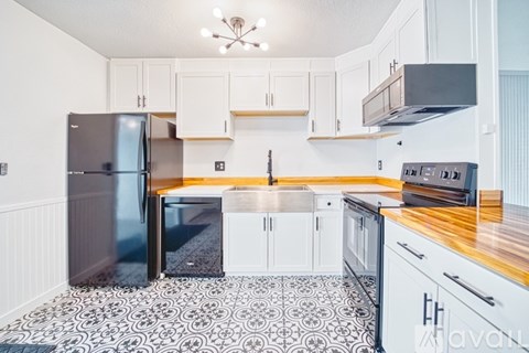 A kitchen with a black fridge and a black stove top oven.