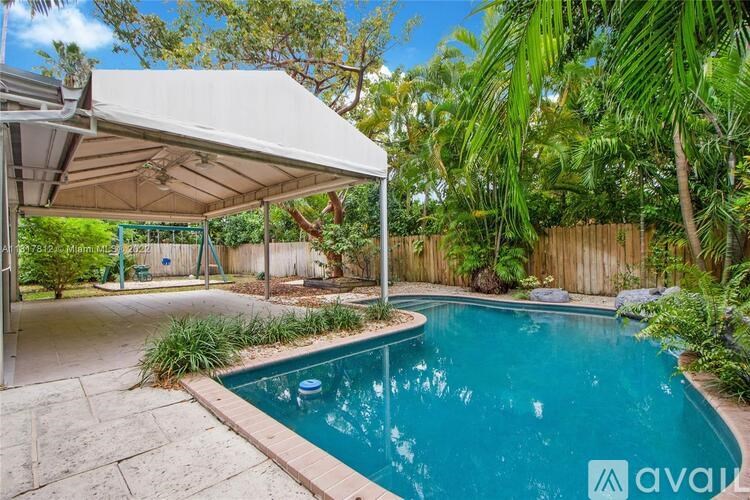 A pool area with a canopy and a wooden fence.