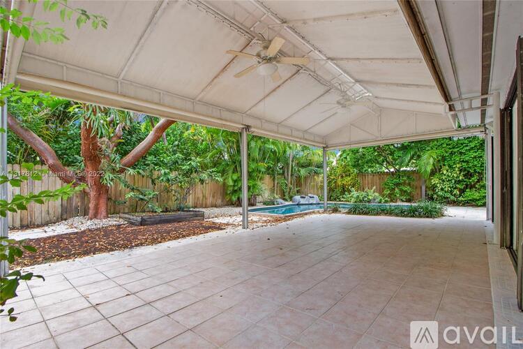 A patio area with a white canopy and a pool in the background.