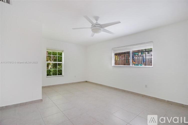 A room with a ceiling fan and two windows.