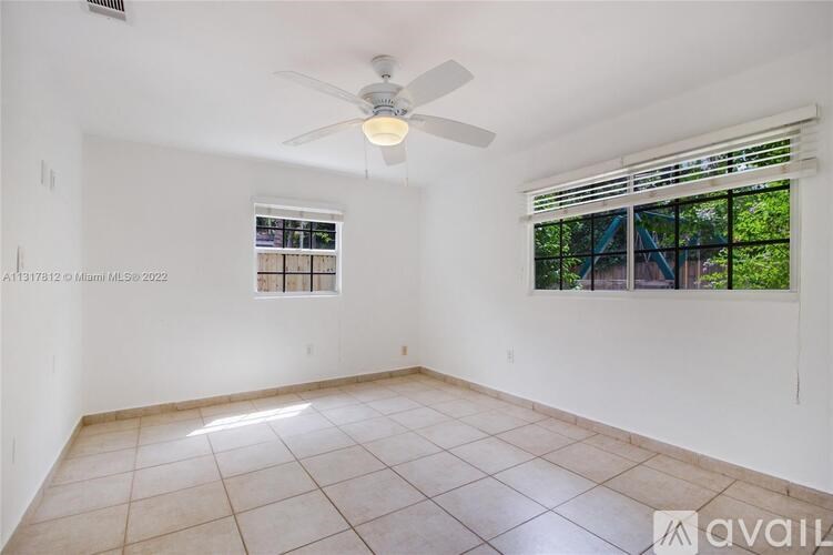 A room with a ceiling fan and a window with blinds.