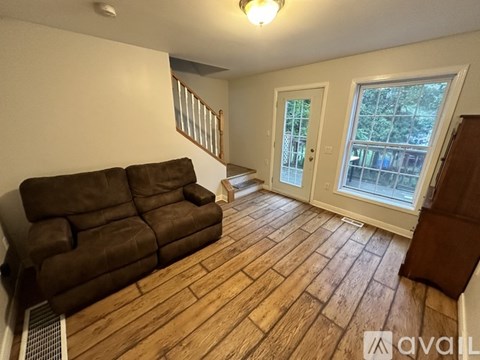 A living room with a brown couch and wooden flooring.