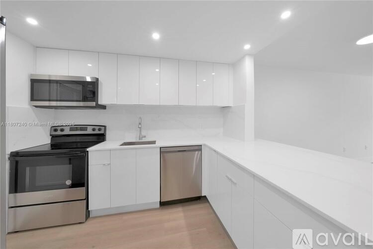 A modern kitchen with white cabinets and stainless steel appliances.