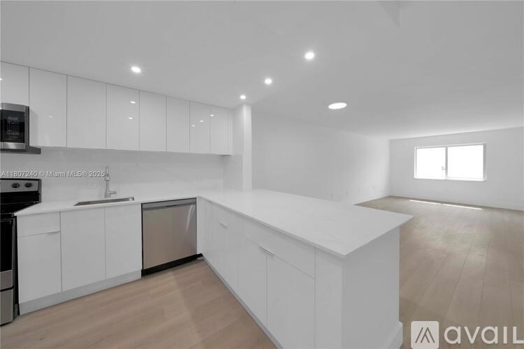 A modern kitchen with white cabinets and a wooden floor.