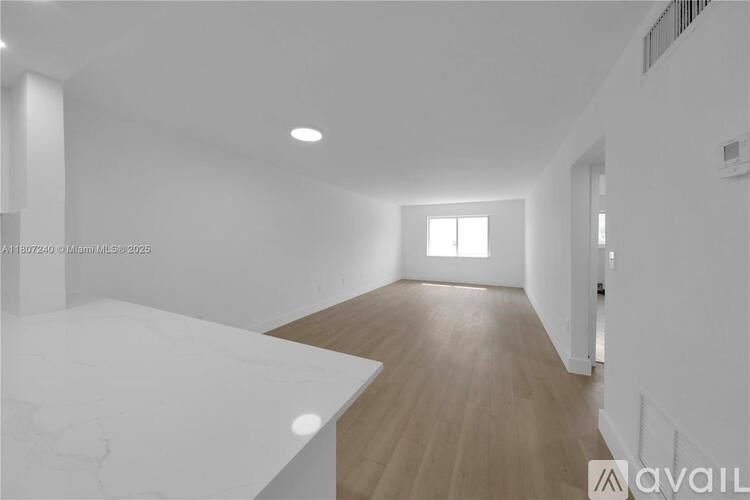 A spacious room with wooden flooring and white walls.