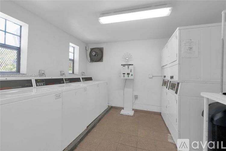 A laundry room with washing machines and a fan on the wall.