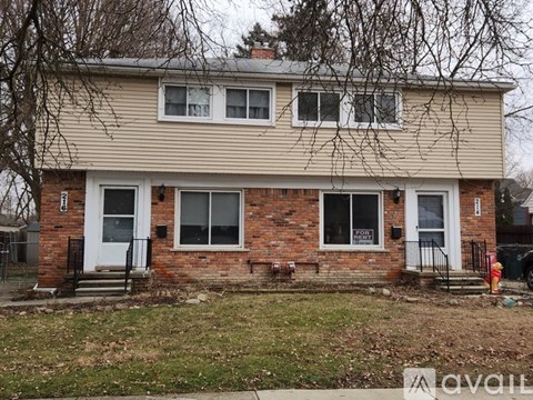 A two-story house with a brick base and siding on the upper level.