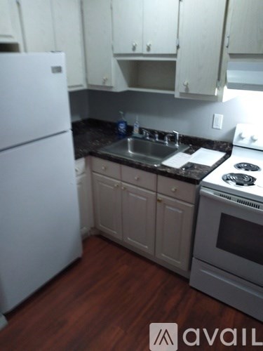A kitchen with a white fridge and a black counter top.