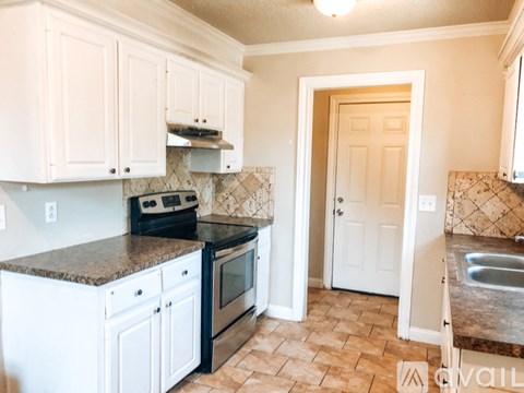 A kitchen with white cabinets and a black stove top oven.