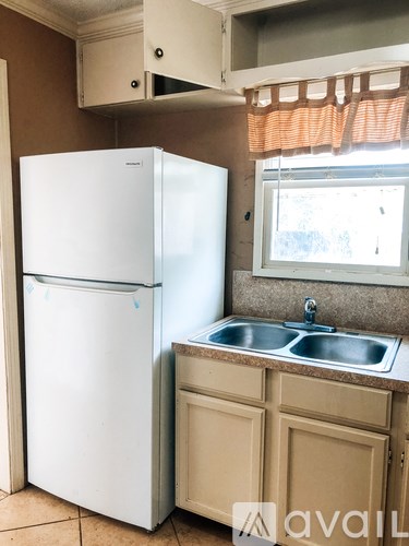 A white refrigerator is in a kitchen next to a sink.