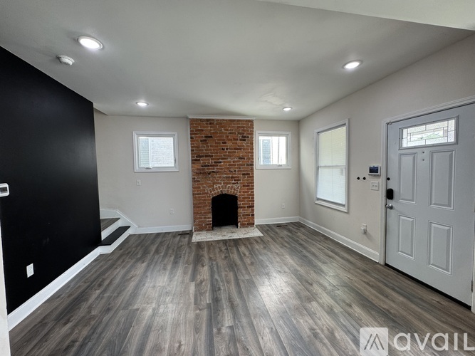 A room with a brick fireplace and wooden floors.
