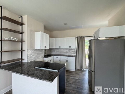 A modern kitchen with white cabinets and a black island.