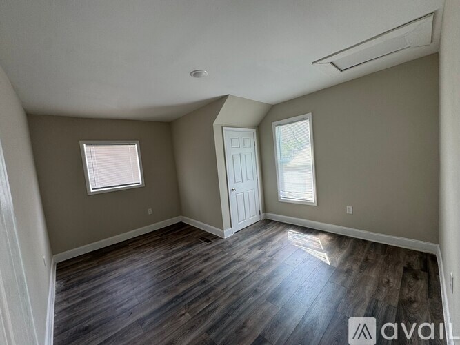 A room with wooden floors and two windows.