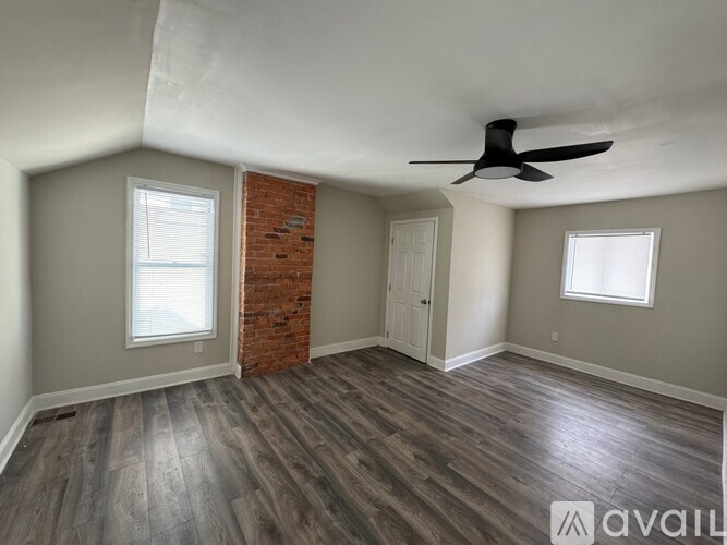 A room with a ceiling fan and wooden flooring.
