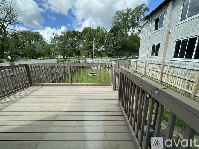 A wooden deck with a railing and a building in the background.