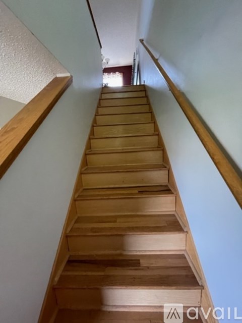 A wooden staircase with a railing on the left side.