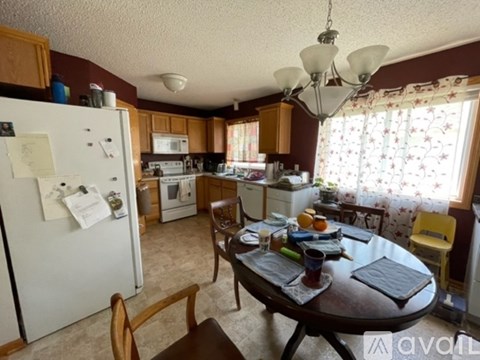 A kitchen with a table set for two and a refrigerator.