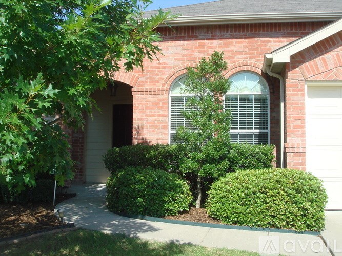 A red brick house with a white garage door and a tree in front.