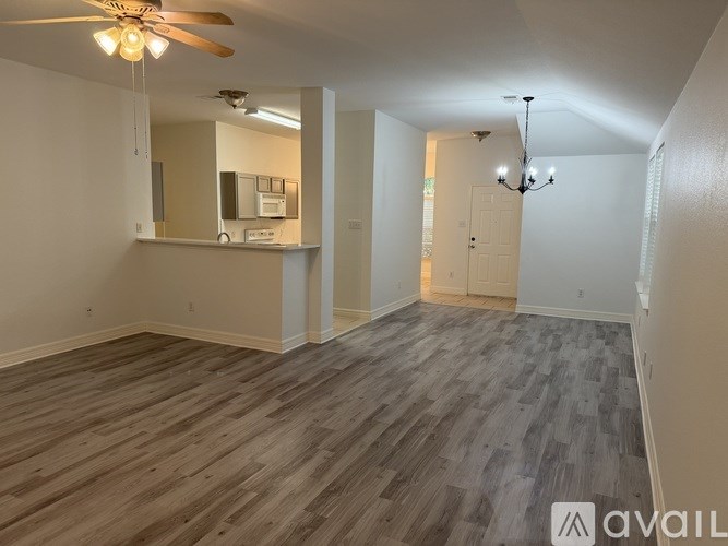 A spacious room with wood flooring and a ceiling fan.