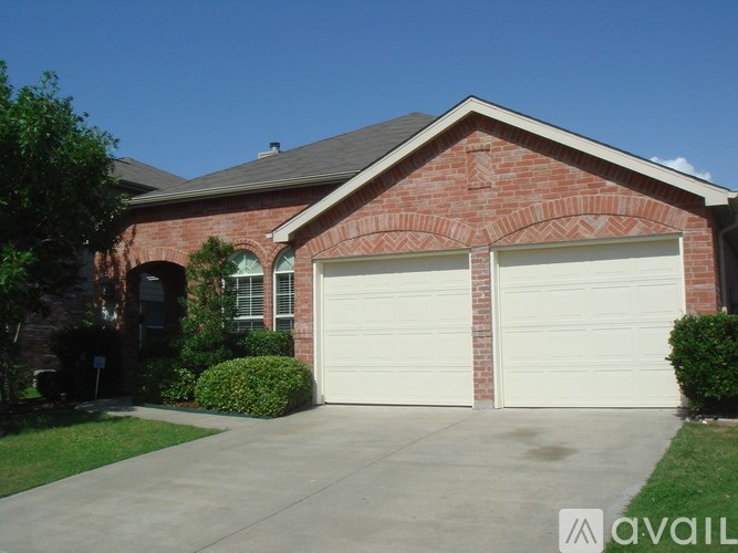 A red brick house with two white garage doors.