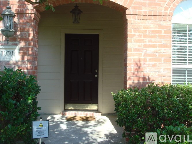 A house numbered 1030 with a black door and a warning sign in front.