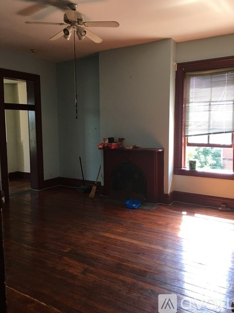 A room with a ceiling fan and a wooden floor.