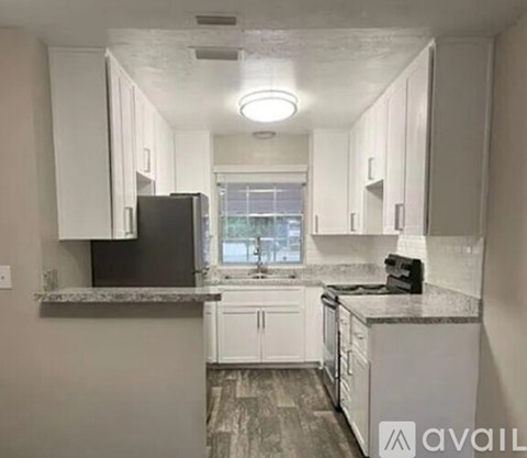 A kitchen with white cabinets and a black refrigerator.