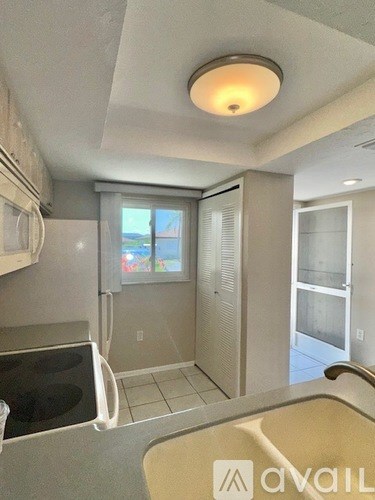 A kitchen with a refrigerator, sink, and a window.