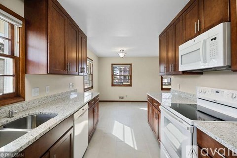 A kitchen with a white microwave above a stove and a sink with a granite countertop.