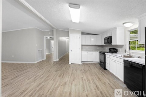 A spacious kitchen with white cabinets and black appliances.