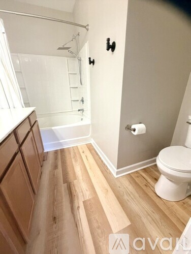 A spacious room with wooden floors and a ceiling fan.