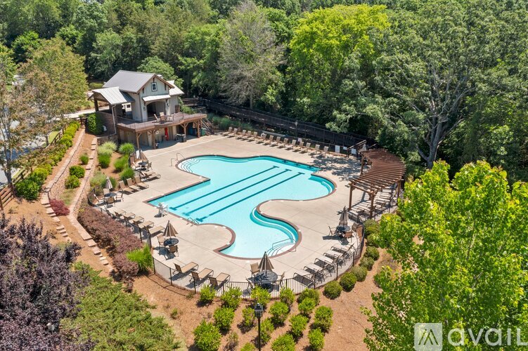 An aerial view of a house with a pool surrounded by trees.
