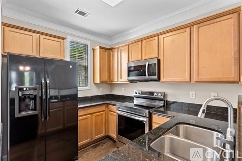 A kitchen with wooden cabinets and black appliances.