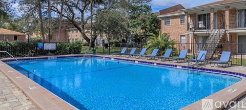 A swimming pool surrounded by lounge chairs and trees.