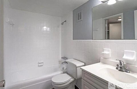 A white bathroom with a toilet, sink, and mirror.