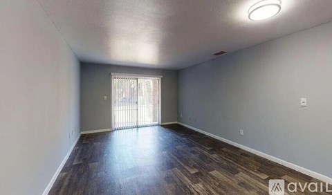 A room with wooden flooring and a window with blinds.