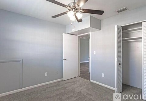 A room with a ceiling fan and a door leading to another room.