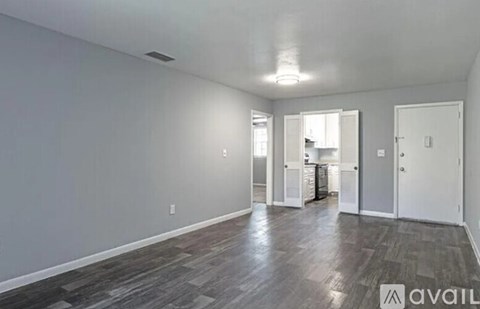 A spacious room with wood flooring and white walls.