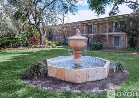 A fountain in the middle of a grassy area in front of a building.