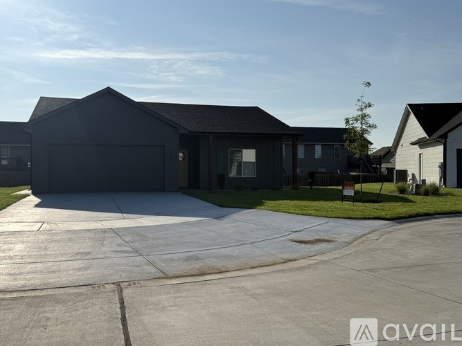 A modern house with a large driveway in front.