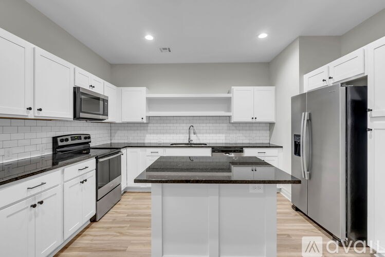 A kitchen with white cabinets and a black countertop.