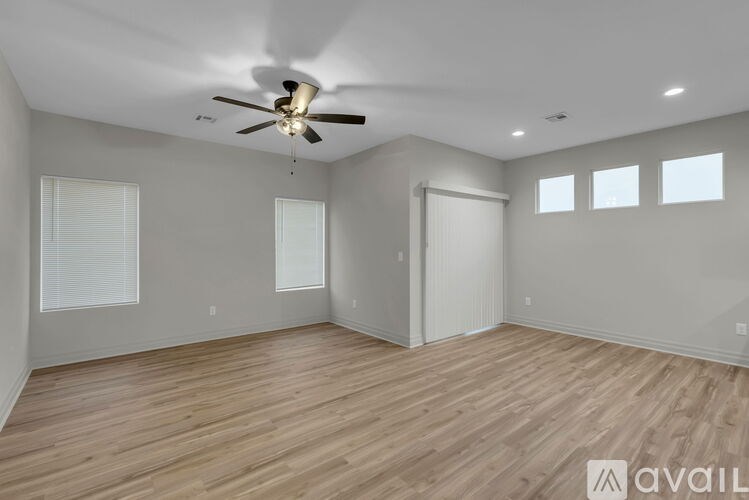 A spacious room with a ceiling fan and wooden flooring.