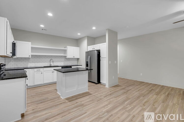 A kitchen with white cabinets and a black countertop is available for rent.