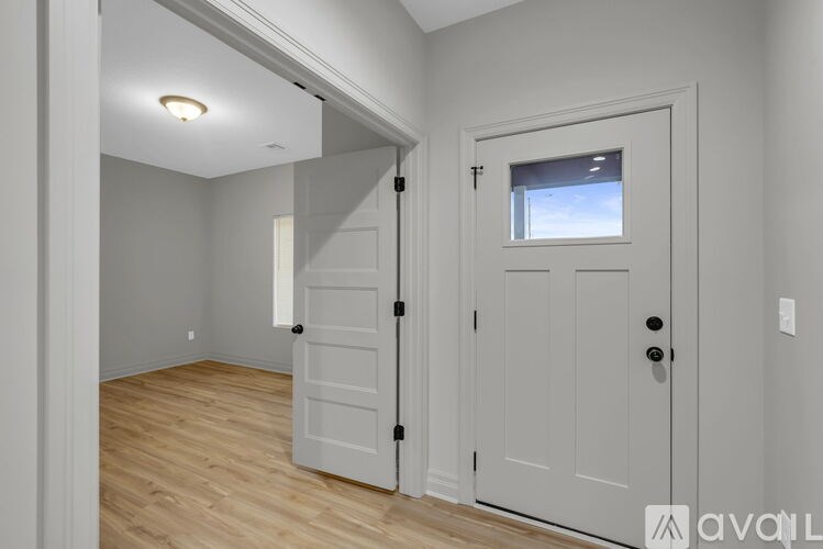 A white door with a black handle is in a room with wooden floors.