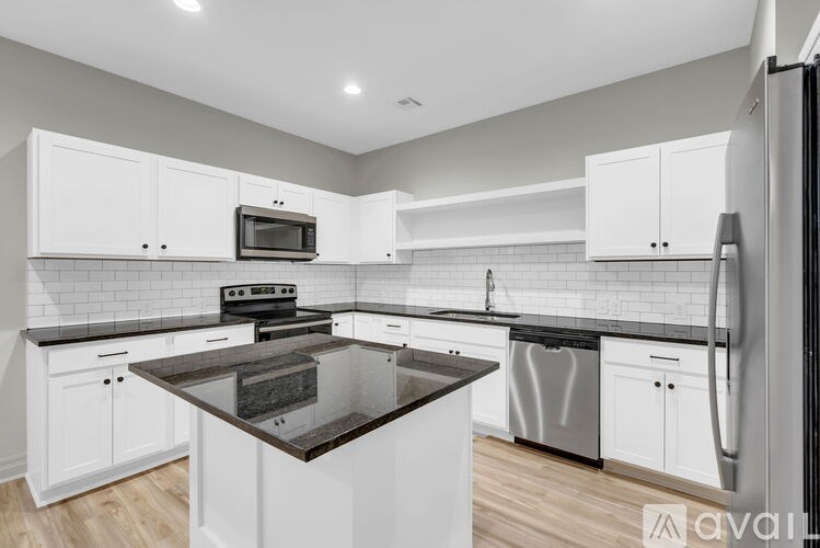 A kitchen with white cabinets and a black countertop.