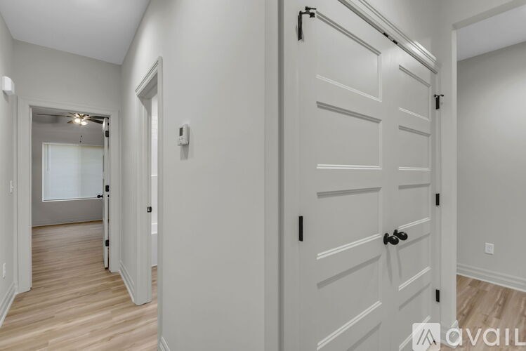 A hallway with a white door and a white wall.