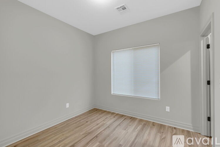 A room with wooden flooring and a window with blinds.