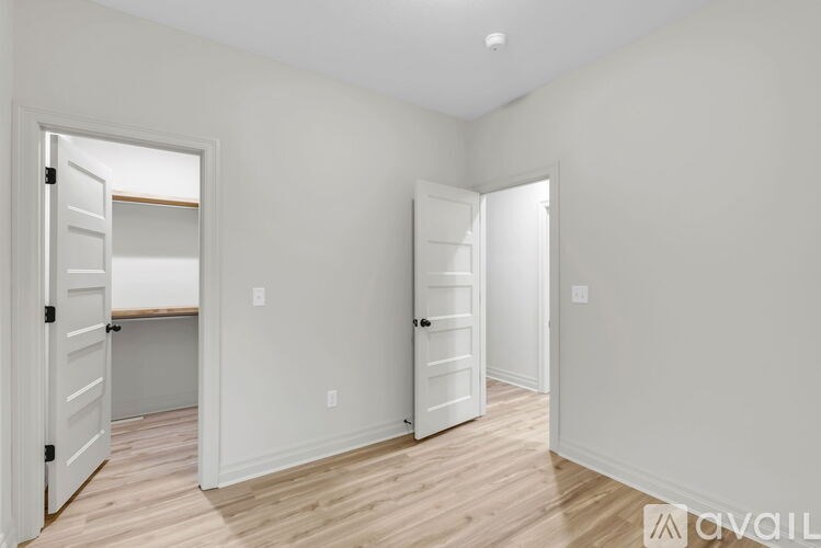 A white room with two doors and a wooden floor.
